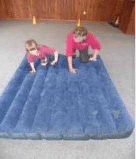 Child and O &amp;amp; M instructor crawling on an airbed.