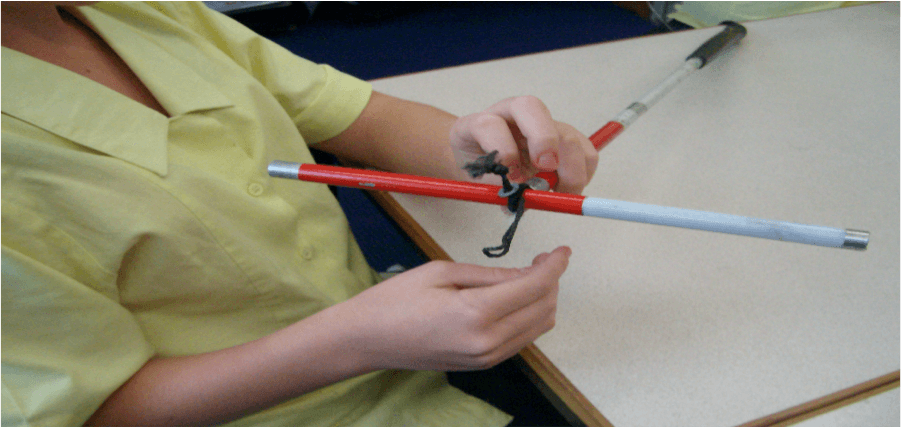 Jesse is using an old piece of cane to loop through the elastic in the cane being fixed.