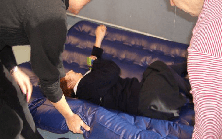 Student lying on the airbed and the O &amp;amp; M Specialist is lifting the airbed edge.