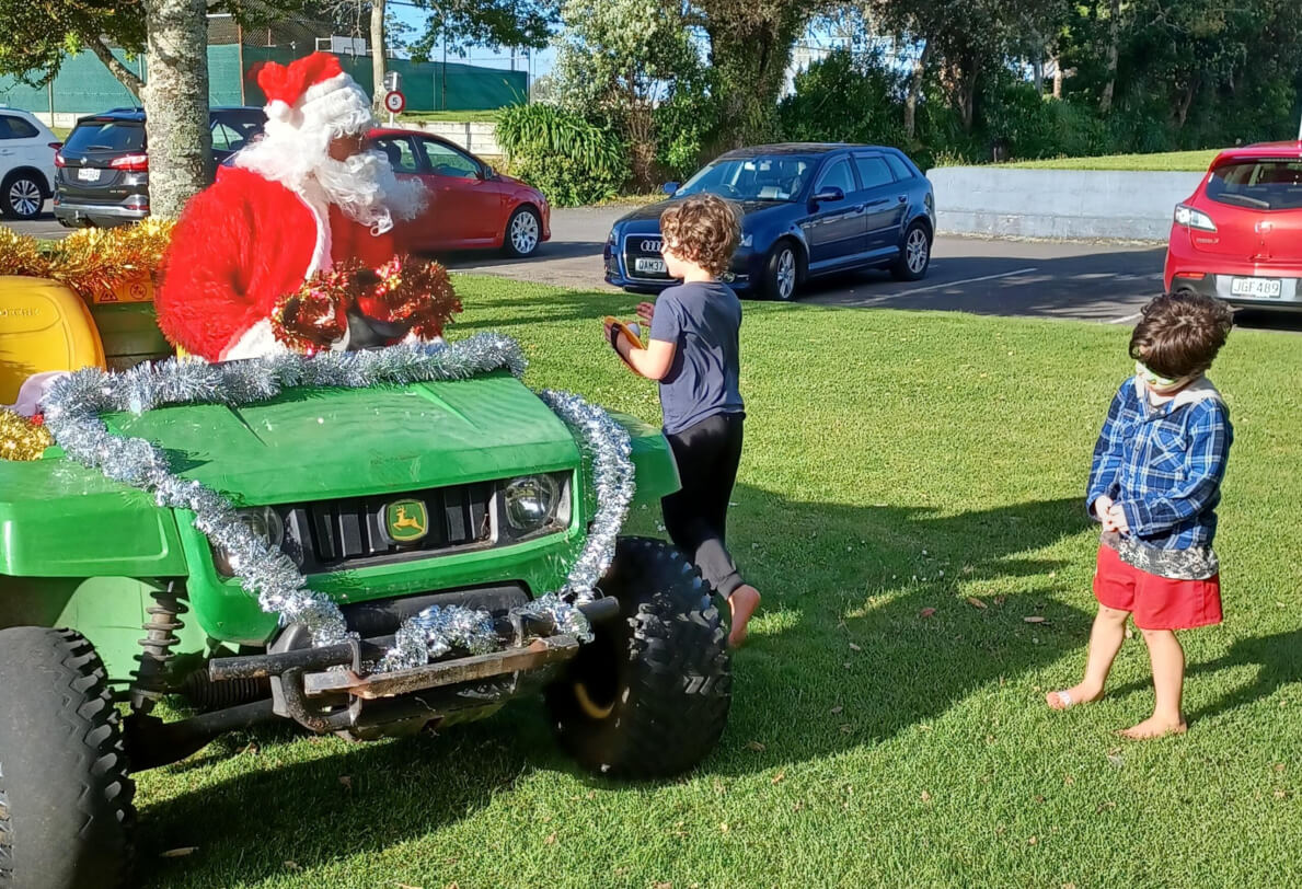 Figure 2 - Father Christmas sitting on a green tractor talking to 2 young boys who are standing on the grass next to his tractor.