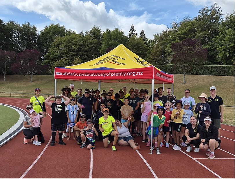 Figure 1 A group photo of the BLENNZ Hamilton athletes and their helpers standing under a marquee.